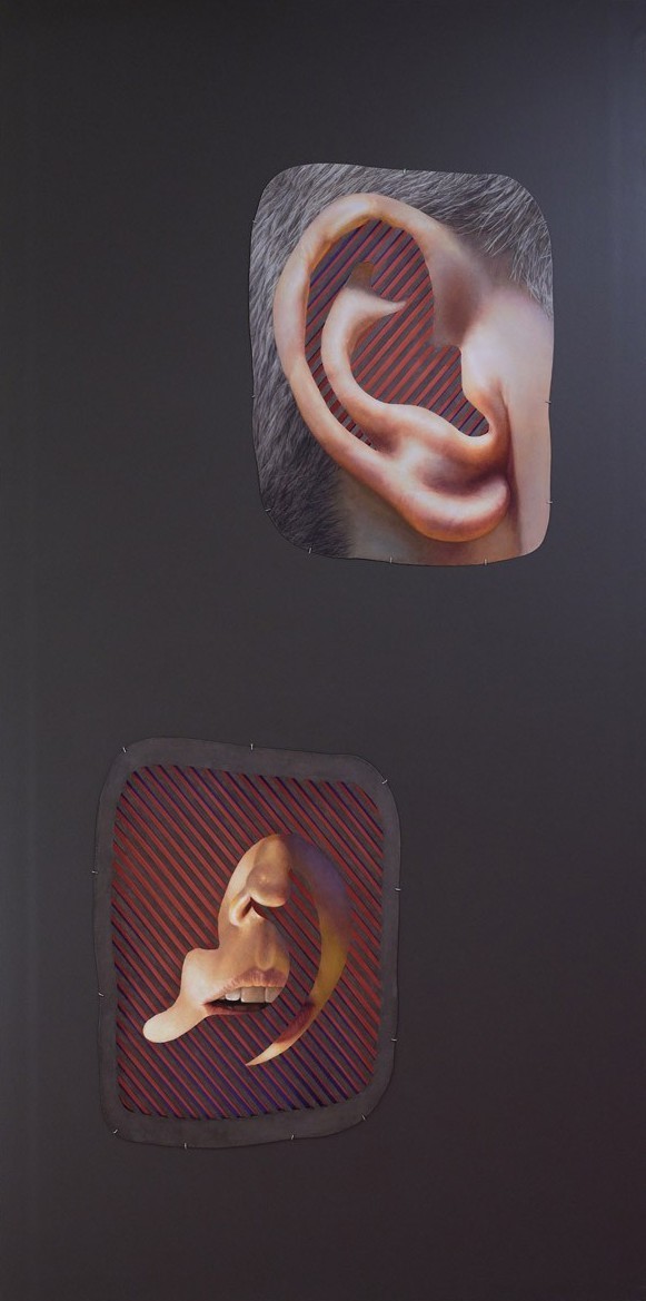 Grey wall with two cut-outs, one of an ear and one of a mouth. Red stripes are inside the ears and surround the mouth.